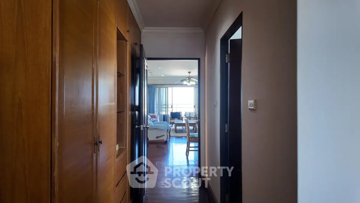 Spacious hallway leading to a bright living room with elegant furnishings and large windows.