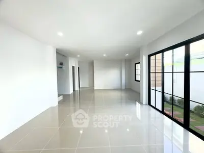 Spacious modern living room with large windows and glossy tiled floors.