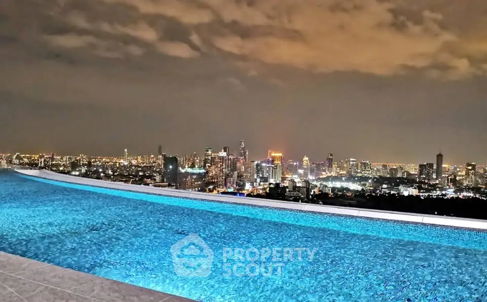 Stunning rooftop infinity pool with breathtaking city skyline view at night.