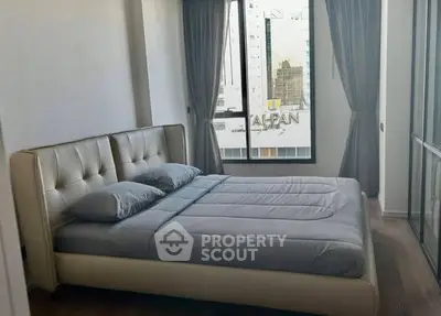 Modern bedroom with large window and city view, featuring a stylish bed and elegant curtains.