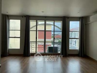 Spacious living room with large windows and wooden flooring, offering a bright and airy atmosphere.