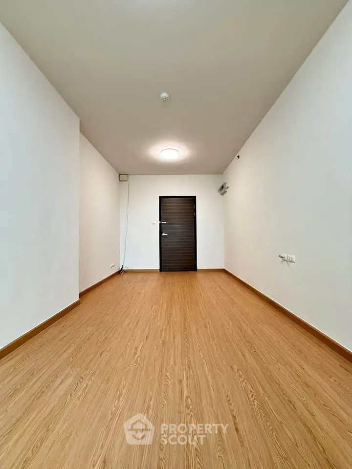 Spacious empty room with wooden flooring and modern lighting, perfect for customization.