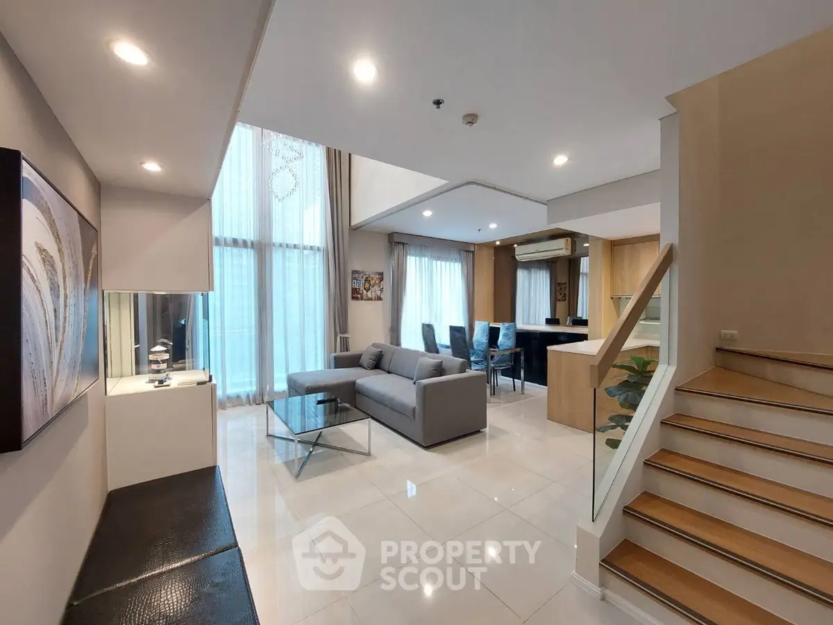 Luxurious open-plan living room with modern furniture and elegant staircase