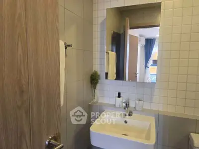 Modern bathroom with sleek sink and mirror, featuring elegant tile design.