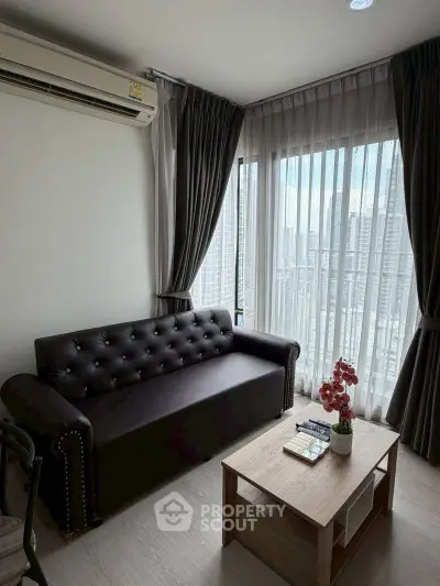 Modern living room with city view, featuring a sleek black sofa and elegant decor.