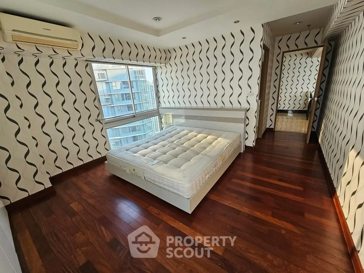 Spacious bedroom with modern design and large window offering city views.