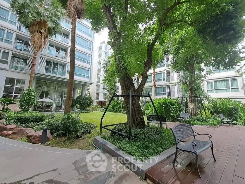 Lush garden area in modern apartment complex with seating and greenery