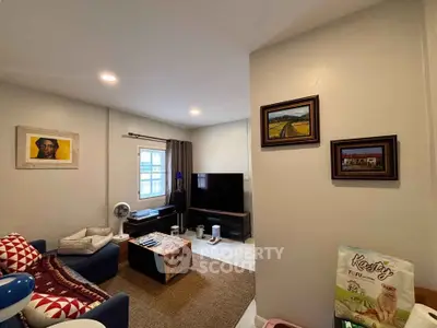 Cozy living room with modern decor, featuring a comfortable sofa, wall art, and a flat-screen TV.