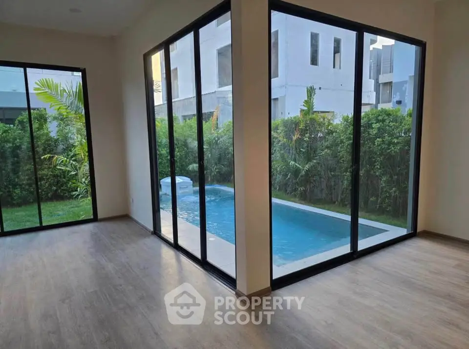Modern corner unit with floor-to-ceiling windows overlooking private pool and lush garden.