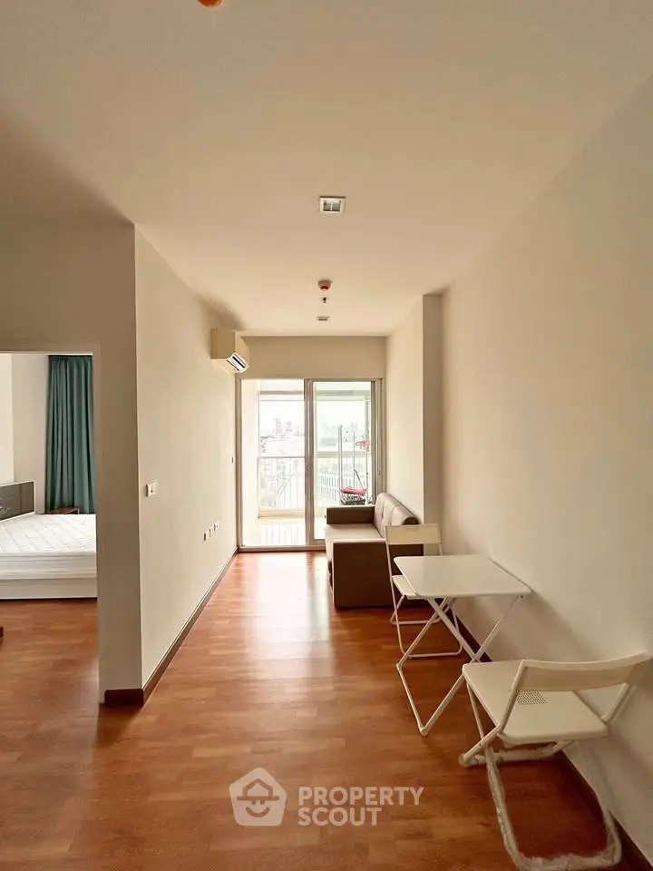 Spacious apartment with wooden flooring and balcony access, featuring a cozy living area and modern design.