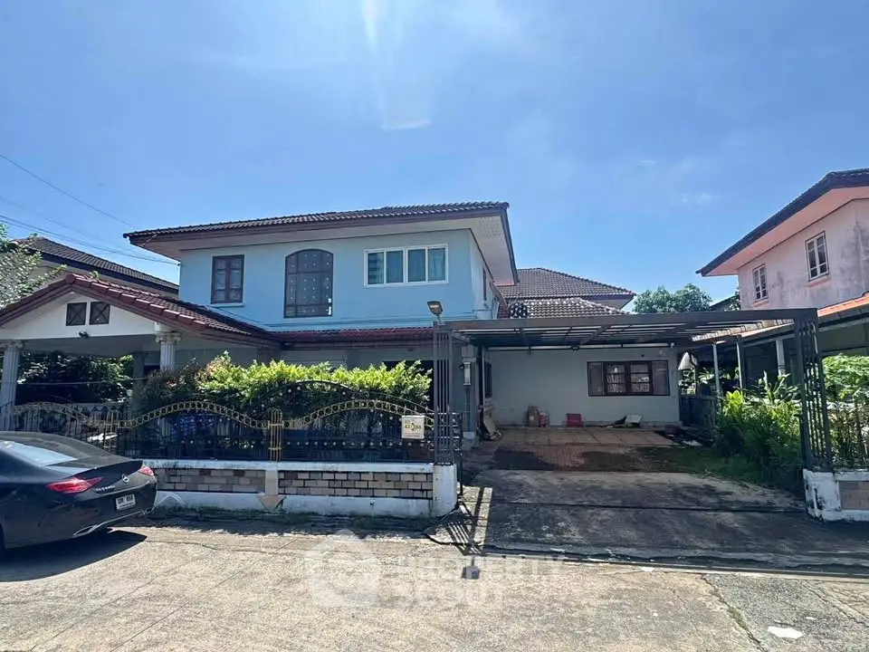 Charming two-story house with driveway and lush greenery in a serene neighborhood.