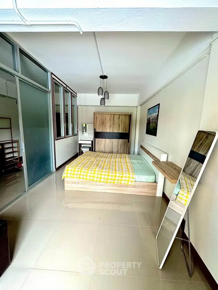 Spacious bedroom with modern decor and large mirror, perfect for comfortable living.