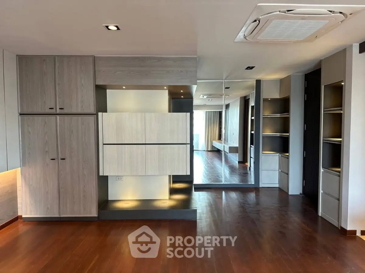 Spacious modern living room with wooden flooring and built-in storage cabinets.