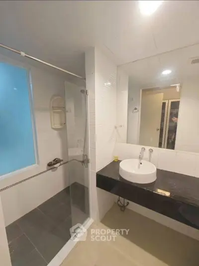 Modern bathroom with glass shower and sleek black countertop