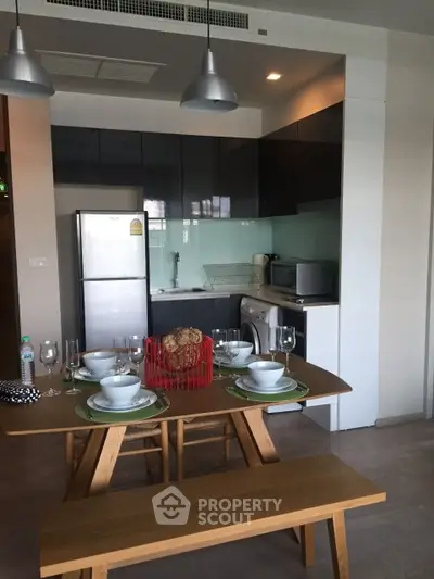 Modern kitchen with dining area, featuring sleek appliances and stylish lighting, perfect for contemporary living.
