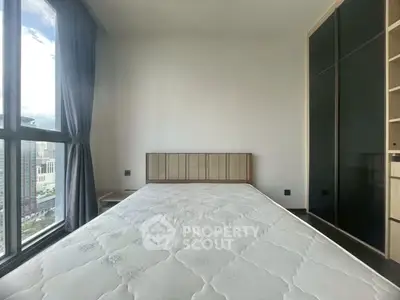 Bright bedroom with large window and modern wardrobe in urban apartment.