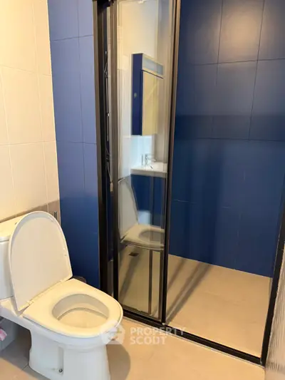 Modern bathroom with blue accent wall and glass shower enclosure