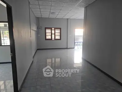 Spacious empty room with tiled flooring and large windows, ideal for customization.