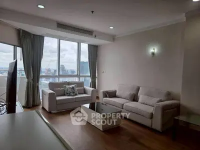 Spacious living room with city view, featuring modern sofas and large windows for natural light.