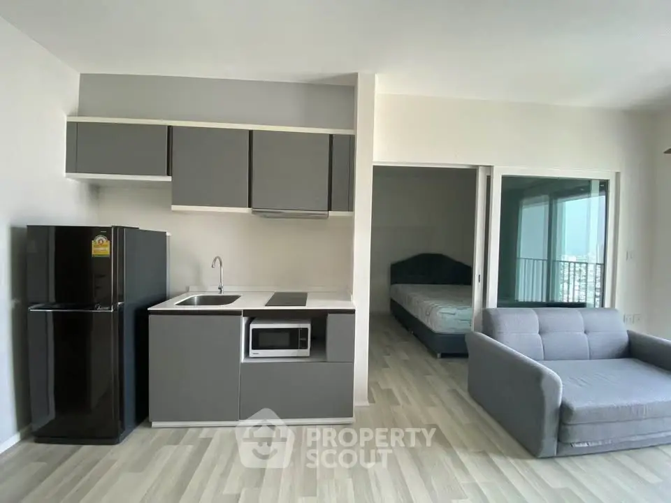 Modern studio apartment with sleek kitchen and cozy living area, featuring a compact design and stylish furnishings.