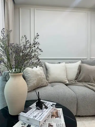Elegant living room with plush gray sofa, decorative pillows, and stylish vase on coffee table.