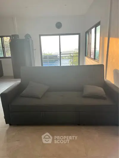 Spacious living room with modern sofa and large windows offering natural light and scenic views.