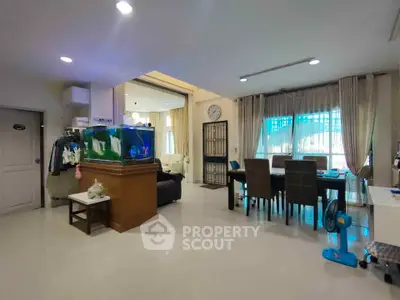 Spacious living room with dining area and large windows, featuring modern decor and ample natural light.