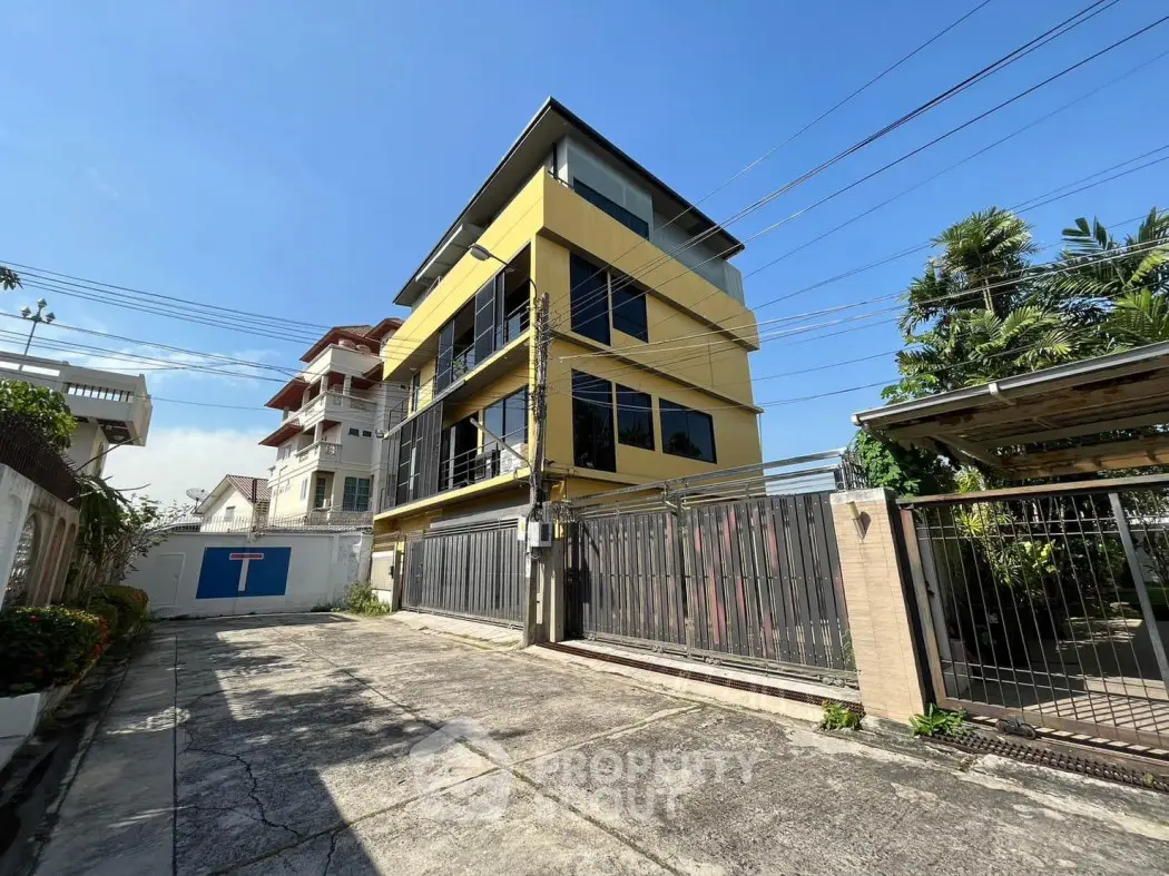 Modern yellow building with gated entrance and clear blue sky