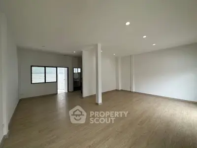 Spacious empty room with wooden flooring and recessed lighting, ideal for customization.