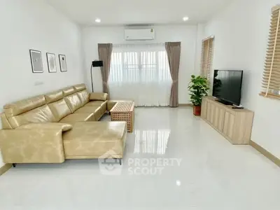 Spacious modern living room with leather sofa and large TV, perfect for relaxation.