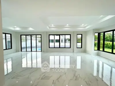 Spacious modern living room with large windows and marble flooring, offering a bright and airy ambiance.