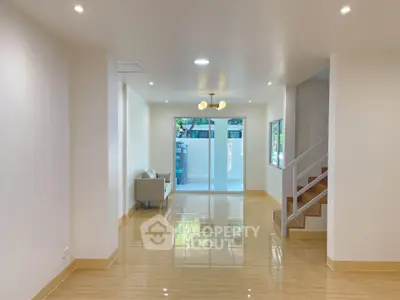 Spacious modern living room with glossy floors and staircase, perfect for family gatherings.
