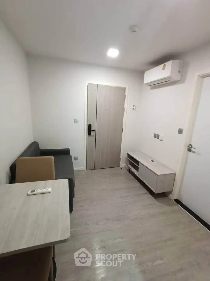 Modern minimalist living room with sleek furniture and air conditioning in a compact apartment.