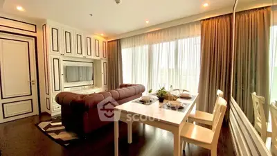 Elegant living room with dining area, featuring large windows and stylish decor.