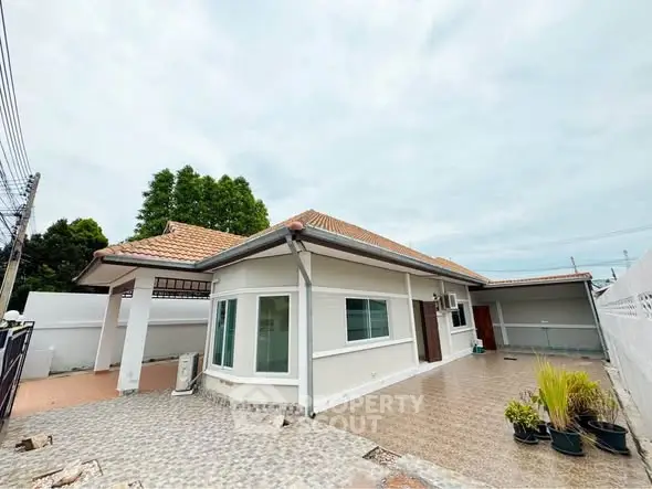 Charming single-story home with tiled patio and lush greenery, perfect for serene living.