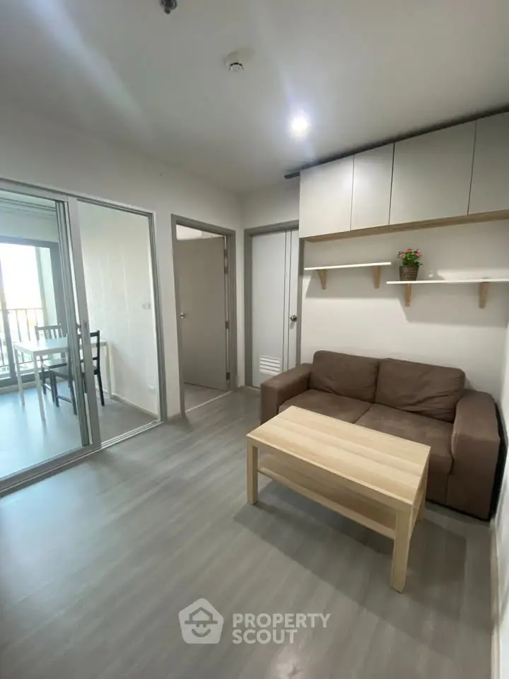 Modern living room with cozy sofa and wooden coffee table, adjacent to dining area with balcony view.