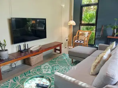 Charming living room with modern decor, large TV, and lush garden view, perfect for relaxation.