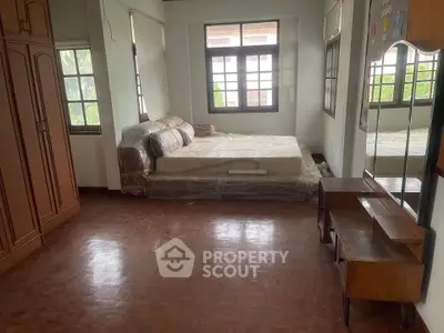 Spacious bedroom with wooden flooring and large windows for natural light