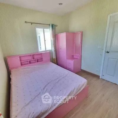 Charming bedroom with pink furniture and natural light, perfect for cozy living.