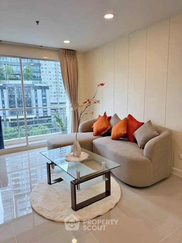 Modern living room with stylish sofa, glass coffee table, and city view through large windows.