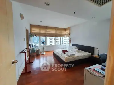 Spacious bedroom with city view and modern furnishings in a high-rise apartment.