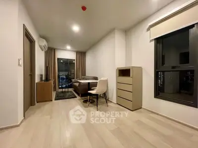 Modern living room with sleek furniture and large window offering city views