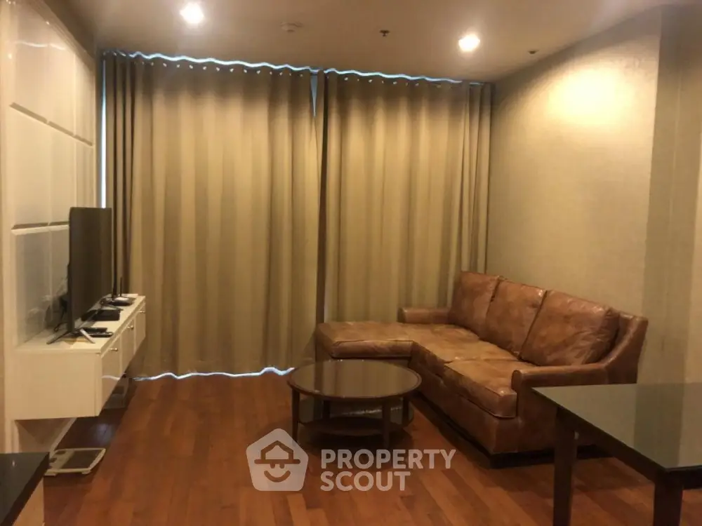 Cozy living room with leather sofa and modern TV setup, perfect for relaxation.
