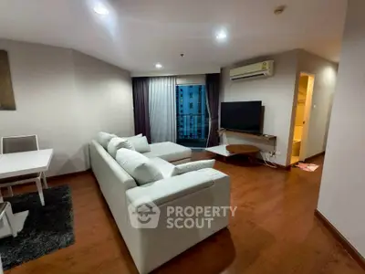 Spacious modern living room with white sofa and wooden flooring in a high-rise apartment.