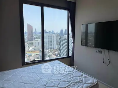 Modern bedroom with city view and wall-mounted TV in high-rise apartment.