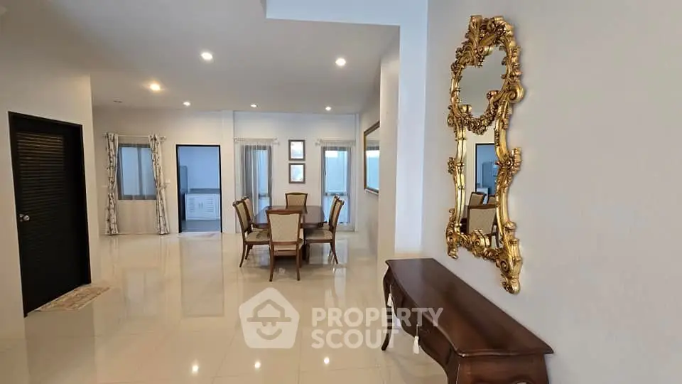 Elegant dining area with ornate mirror and polished floors in spacious home
