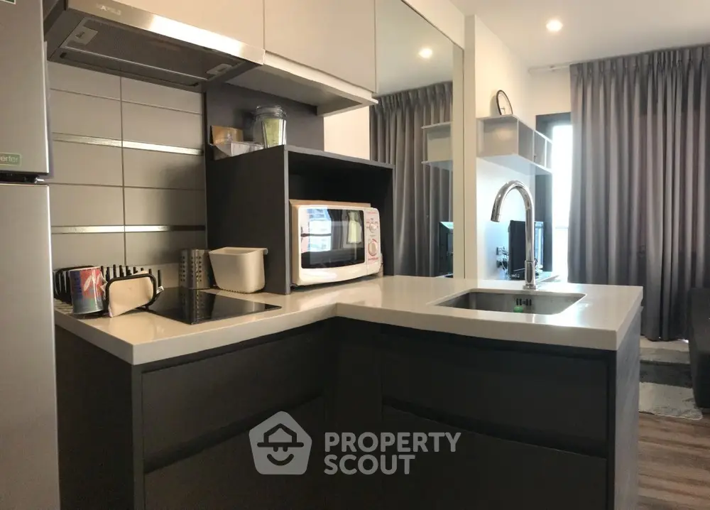 Modern kitchen with sleek cabinetry and built-in microwave in stylish apartment.