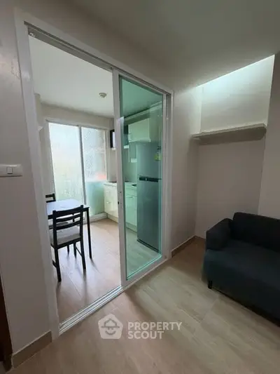 Modern apartment with open kitchen and cozy living area, featuring sliding glass doors.