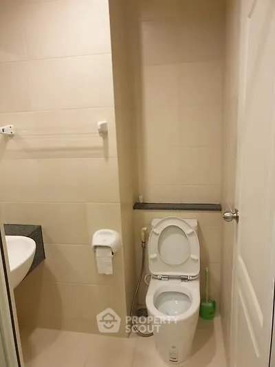 Modern bathroom with sleek fixtures and neutral tiles, featuring a toilet and sink.