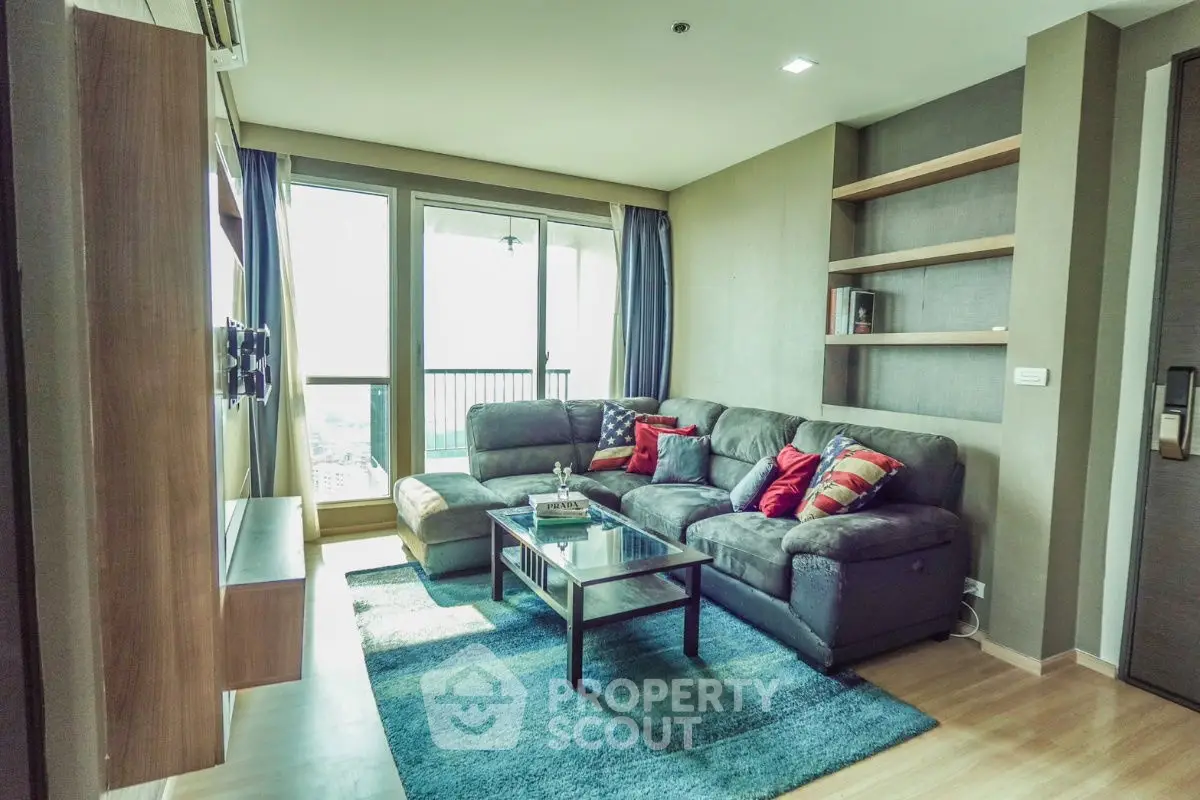 Modern living room with cozy sectional sofa and large windows offering city views.